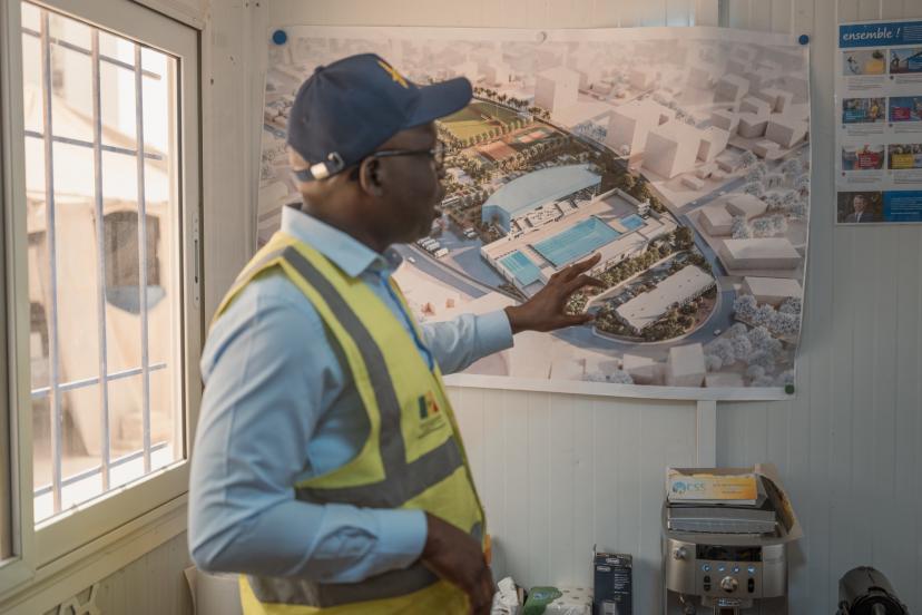 Babacar Senghor, coordonnateur du projet des Jeux Olympiques de la Jeunesse (JOJ), devant les plans de la piscine
