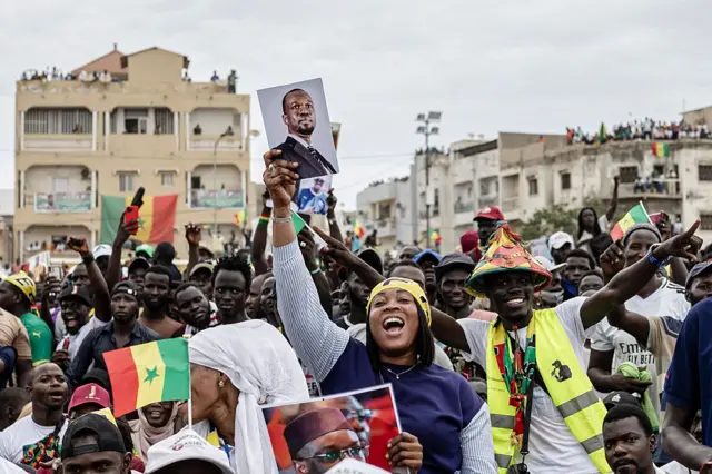 Une partisane du Premier ministre sénégalais Ousmane Sonko danse en tenant un portrait de lui lors d'un rassemblement à Dakar, le 8 novembre 2025. 