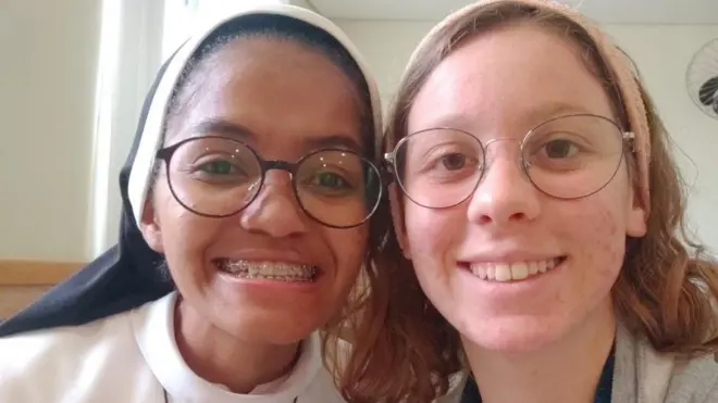 Gros plan sur deux femmes souriant à l'objectif. Celle de gauche porte un habit religieux et celle de droite un bandeau.